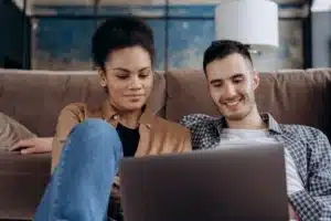Pareja sentada en el sofá mirando el portátil durante una sesión de terapia de pareja online